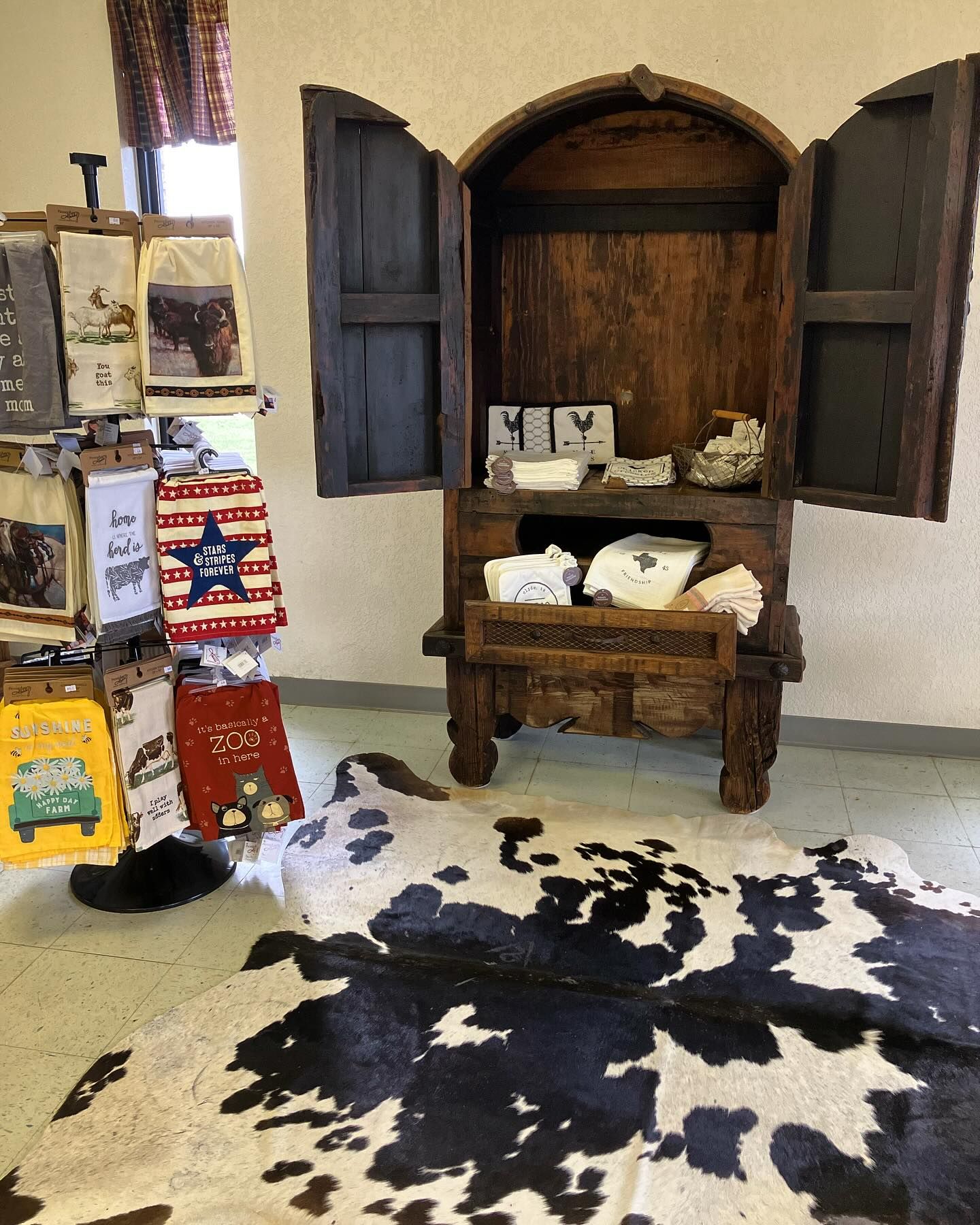 Rustic wooden cabinet with open doors, merchandise on display, cowhide rug.