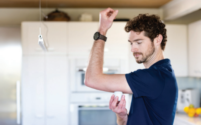 A man in a blue shirt is holding a pill in his hand.