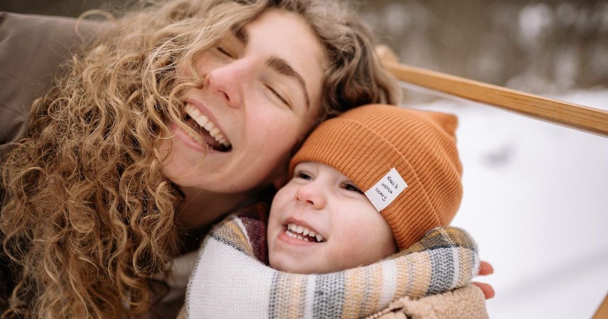 A woman is holding a child in her arms in the snow.