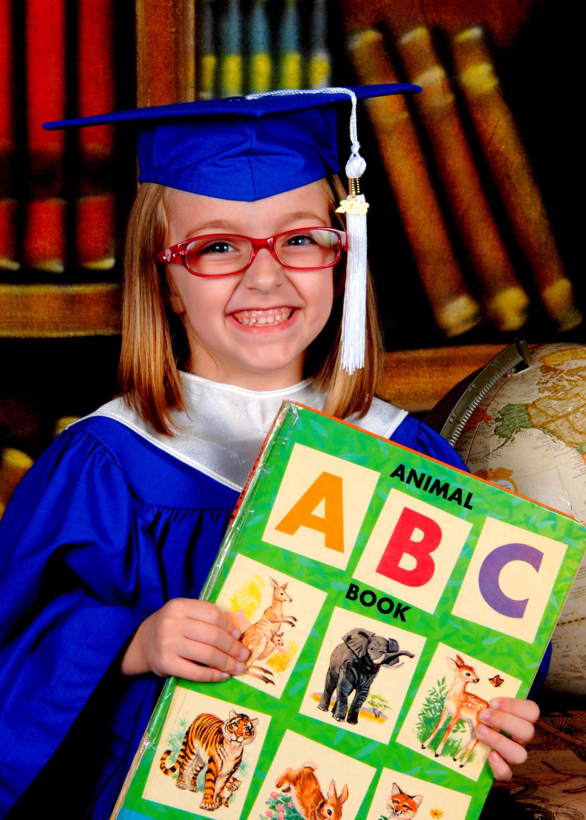 Happy Girl with Eye Glasses While Holding a Book — Austin, TX — Little Munchkins Learning Center