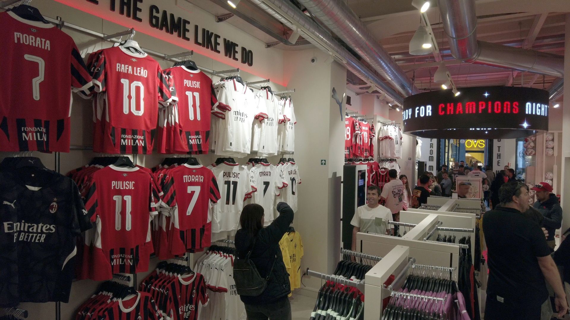 Inside a soccer team store, red and white jerseys on display. People browse the items.