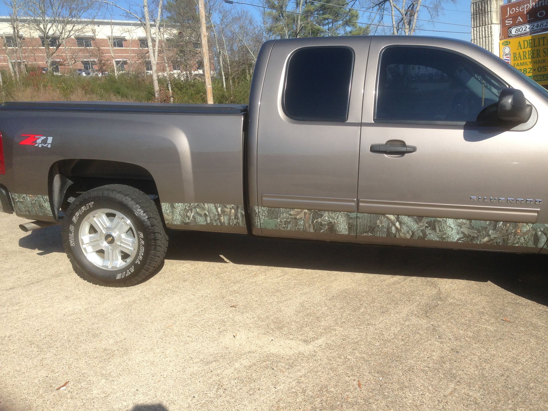 Brown Chevrolet pickup truck with camouflage trim, parked outside on a sunny day.