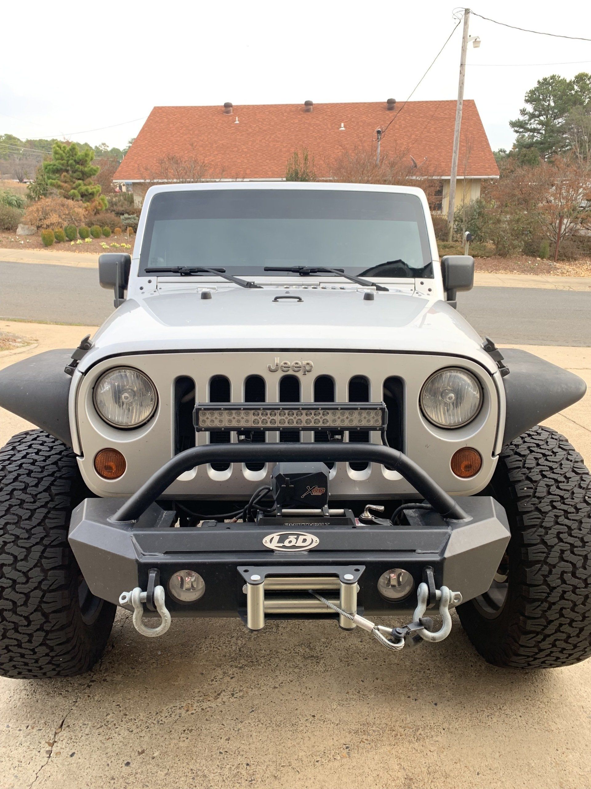 Silver Jeep Wrangler with large tires, front bumper, and LED light bar.
