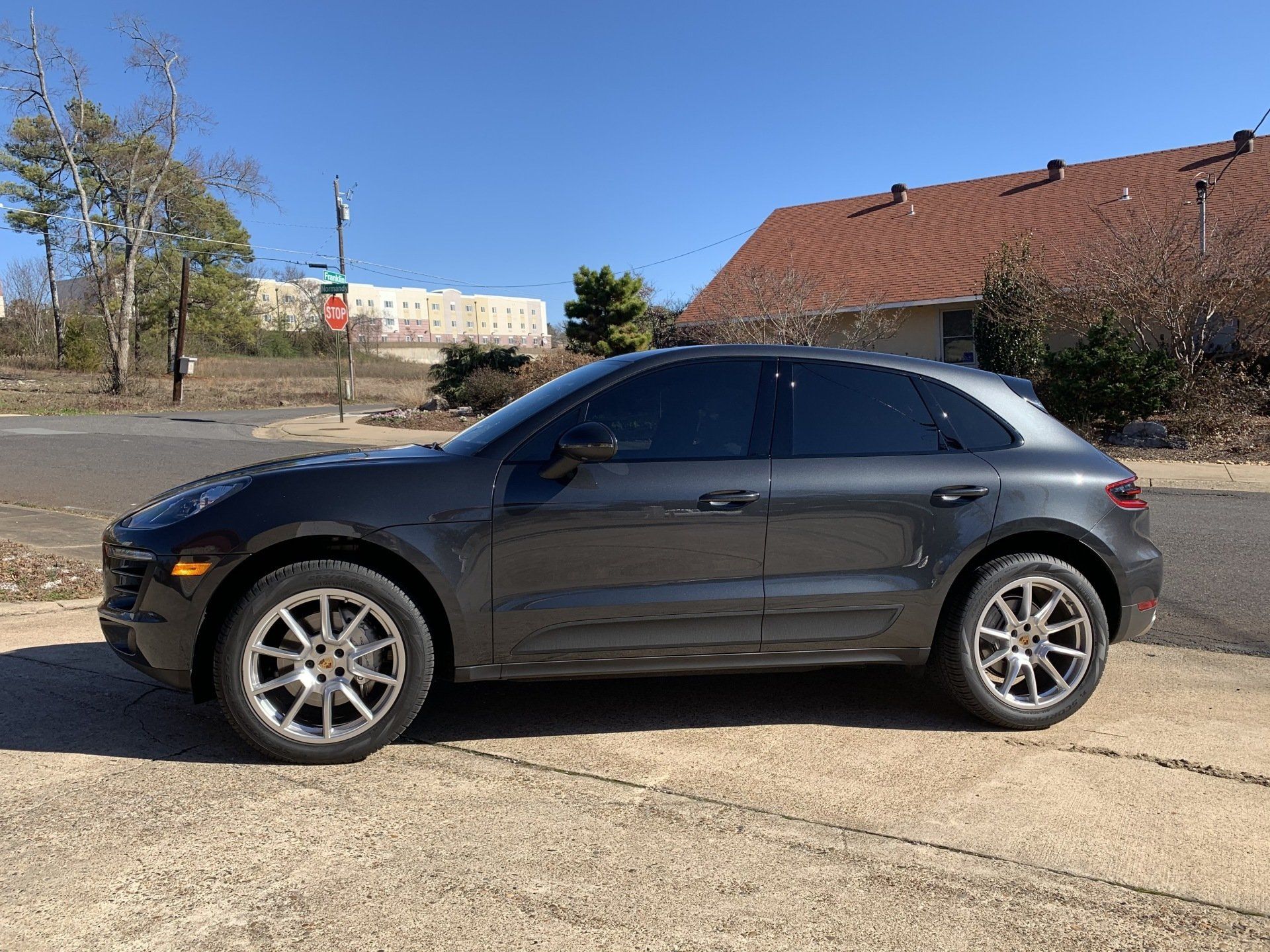 Gray Porsche SUV parked on a concrete surface with tinted windows.