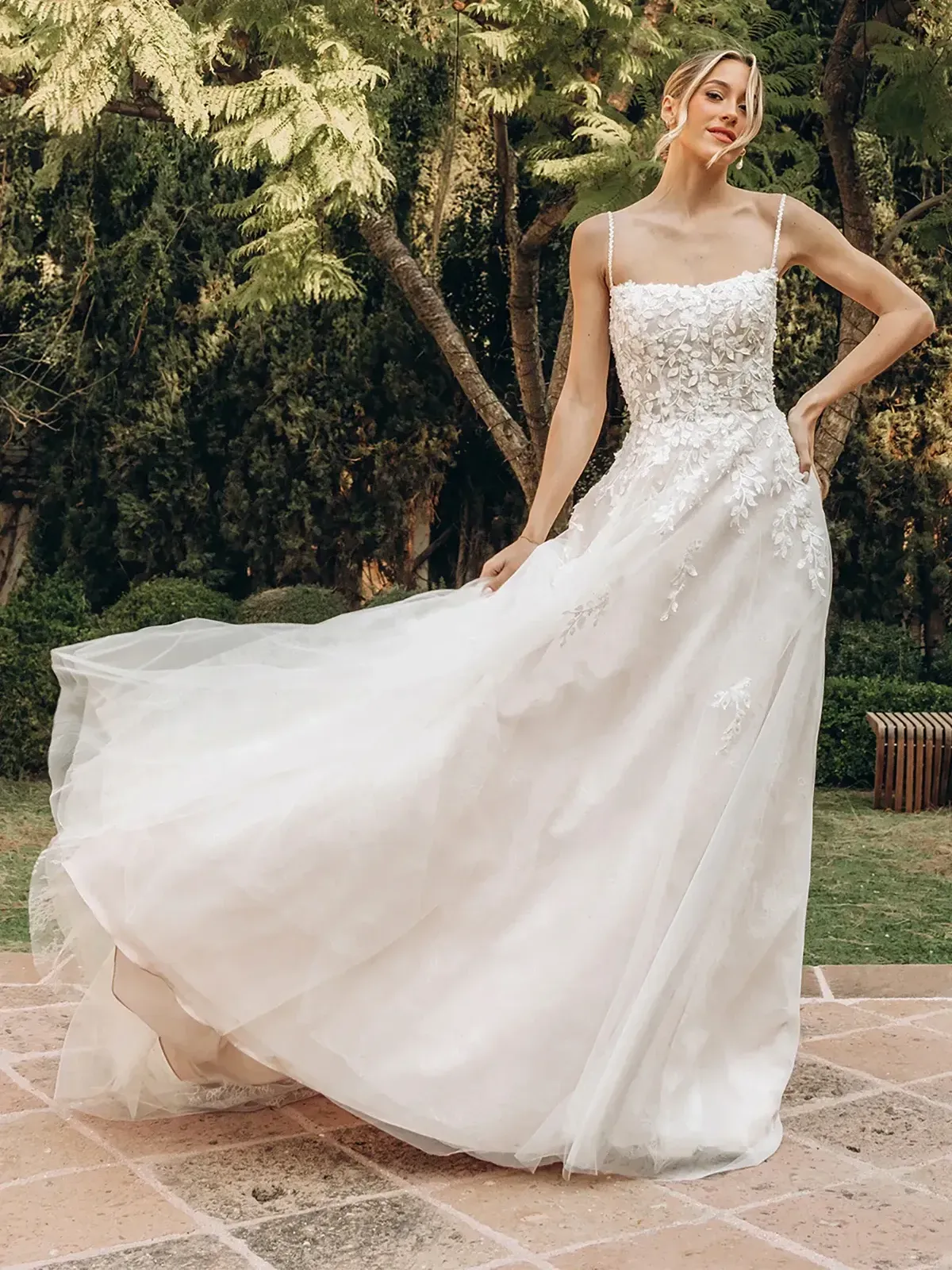 A woman in a white wedding dress is standing on a sidewalk.