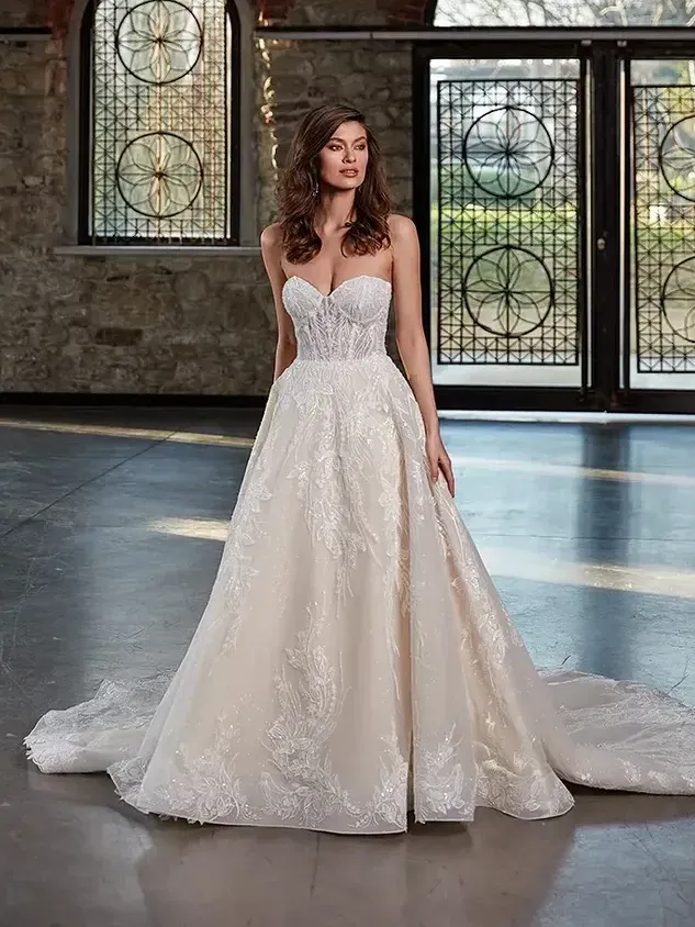 A woman in a wedding dress is standing in a room in front of a window.