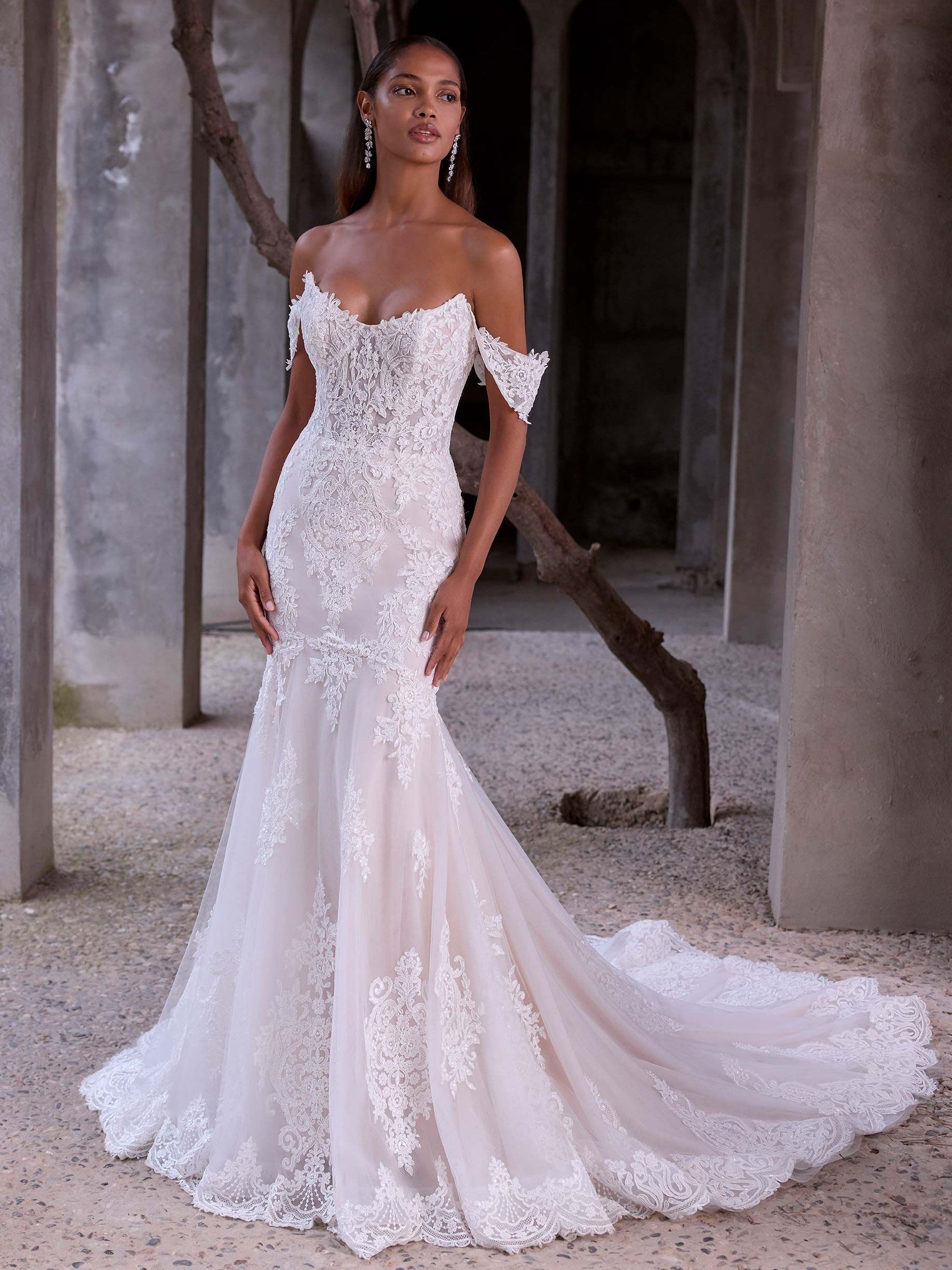 A woman in a white wedding dress is standing next to a tree.