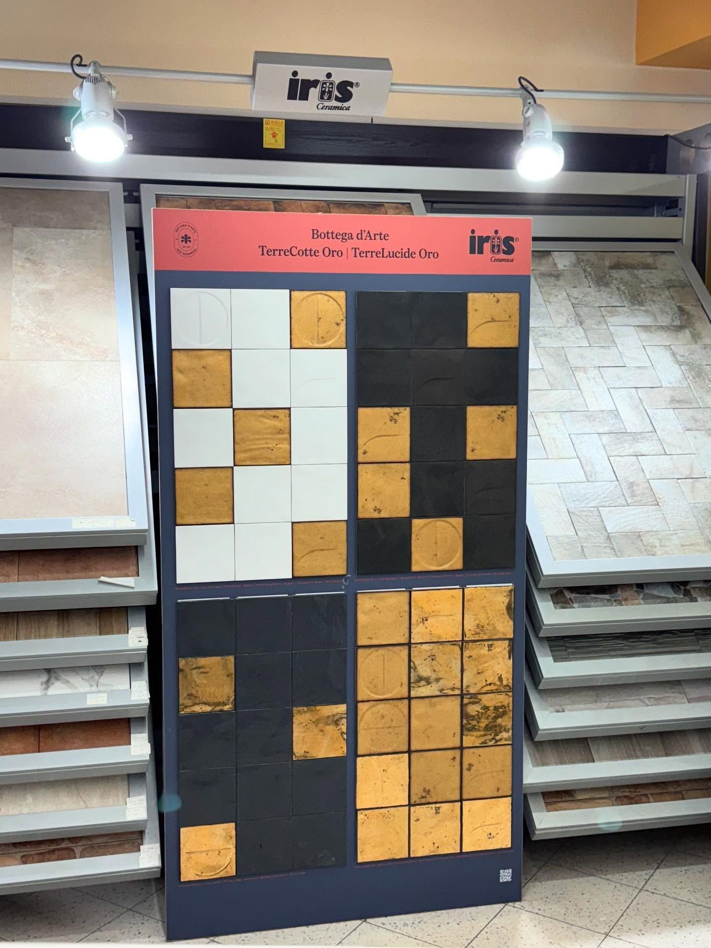 Esposizione di piastrelle del marchio Iris in uno showroom. Piastrelle nei colori bianco, nero e oro.