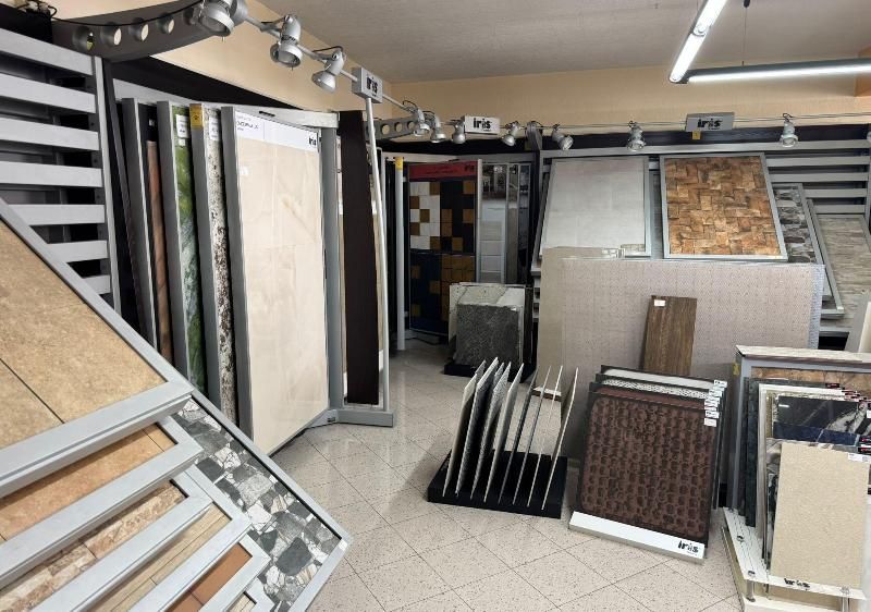 Showroom di piastrelle con varie esposizioni di piastrelle, ben illuminato, che mostra diverse texture e colori.