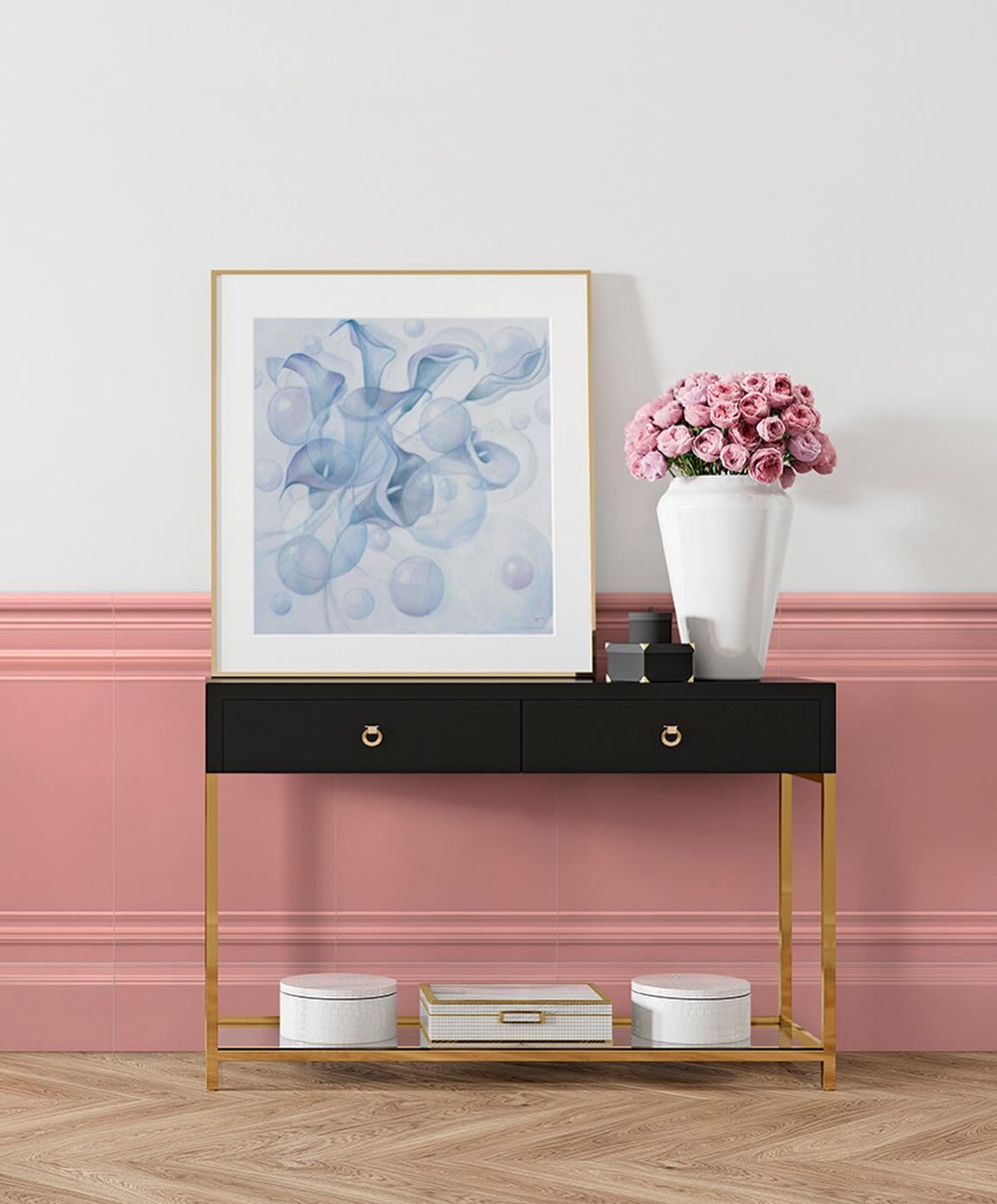 Consolle nera con cornice dorata, parete rosa, quadri, fiori rosa in vaso bianco.