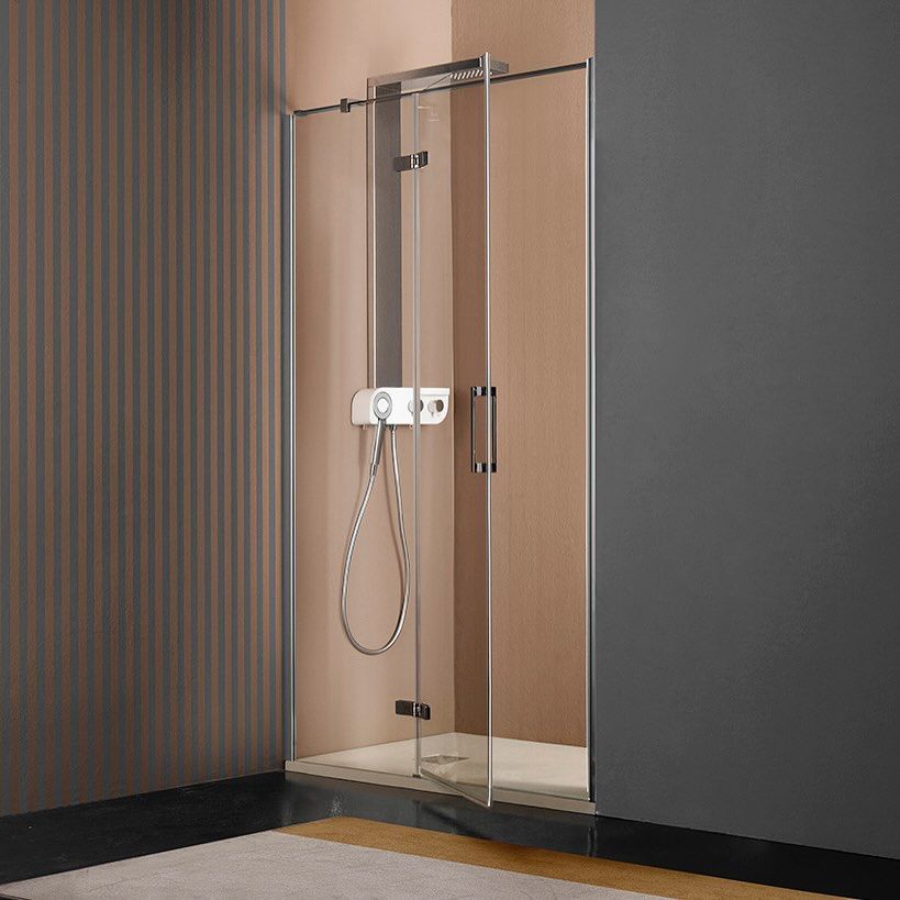 Porta doccia in un angolo, vetro trasparente, ferramenta cromata, pareti beige e grigie.