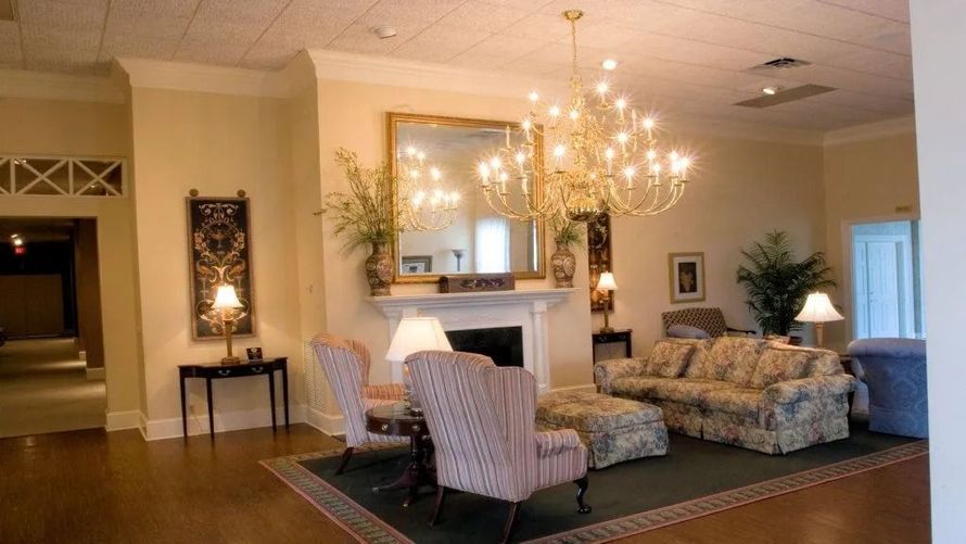 Elegant living room with chandelier, fireplace, striped armchairs, floral sofa, and wood flooring