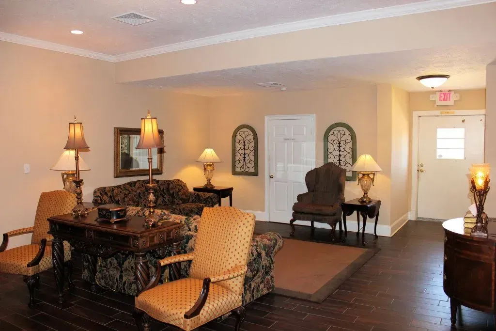 Elegant living room with upholstered chairs, lamps, and dark wood floors in warm lighting