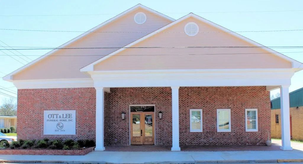 Brick community building with a white-columned entrance and a sign on the left side.