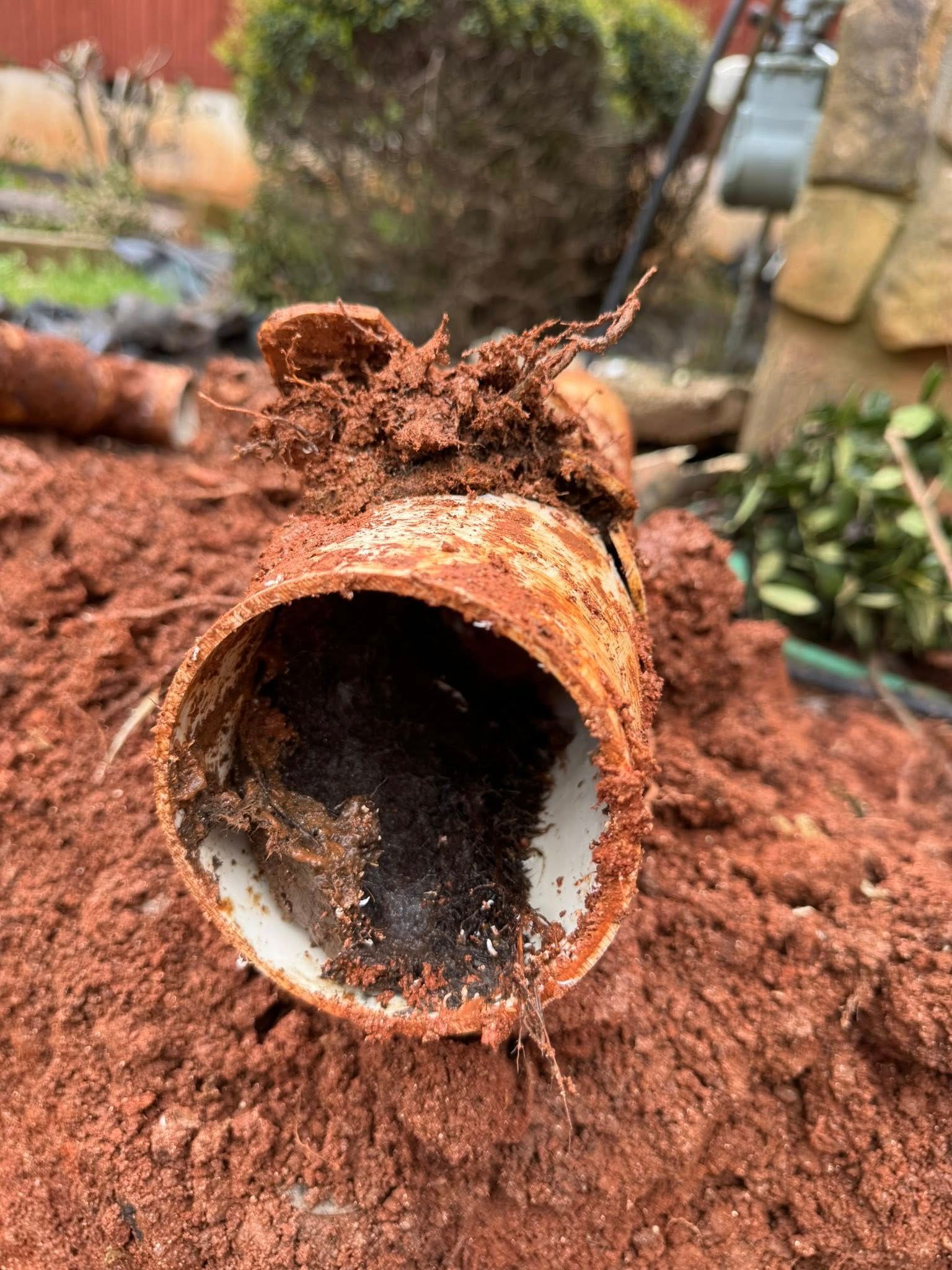 A rusty pipe is sitting on top of a pile of dirt.