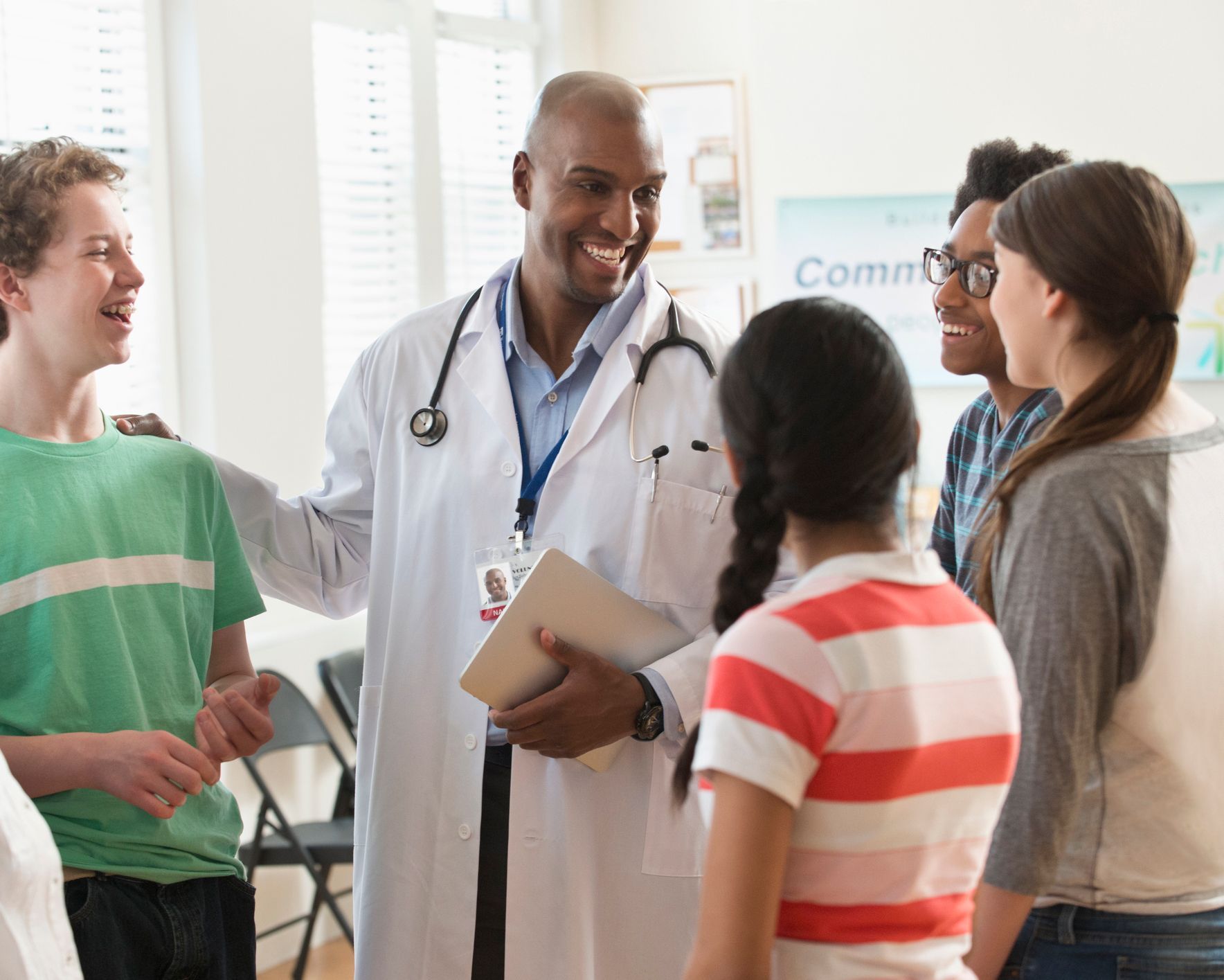 A doctor is talking to a group of children in a room.