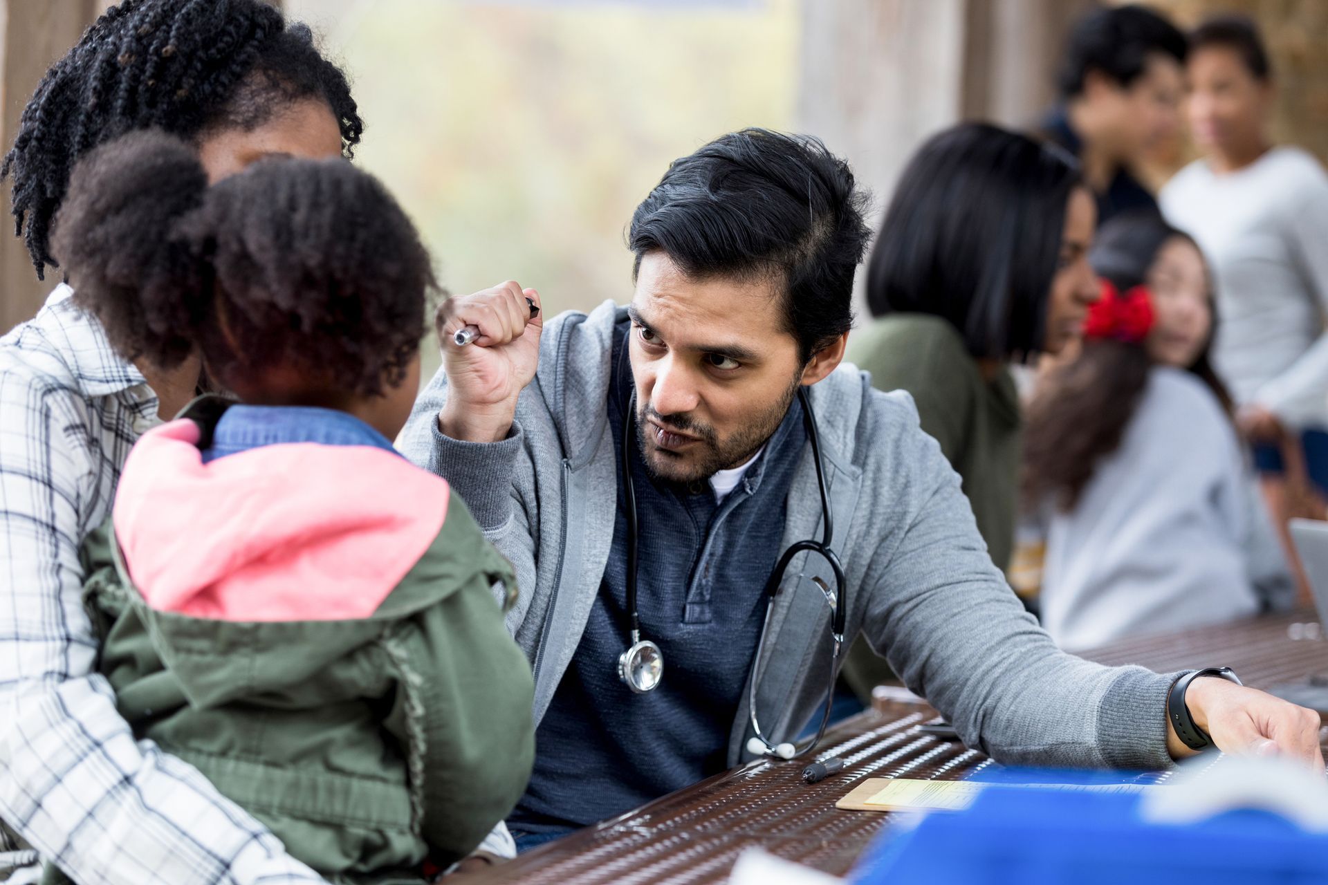 A doctor is talking to a little girl while sitting at a table.