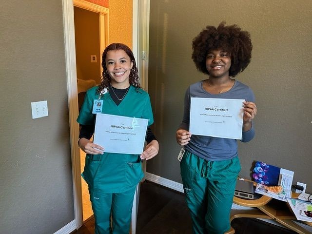 Two nurses are standing next to each other in a room holding certificates.