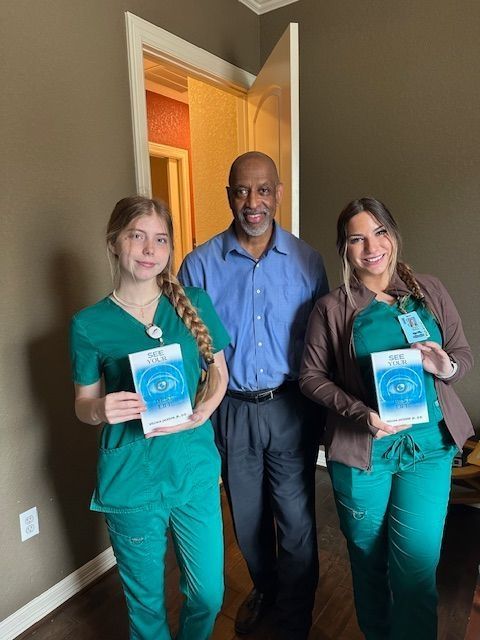A man and two nurses are standing next to each other holding books.