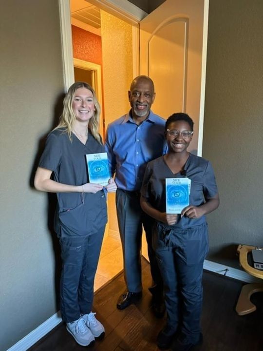 A man and two women are standing next to each other holding books.