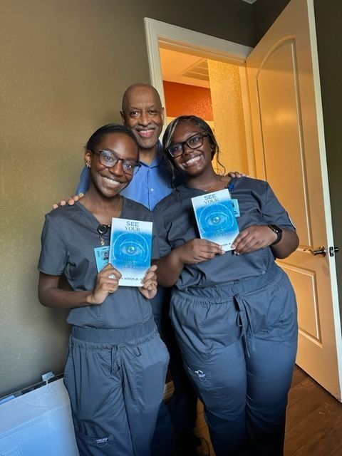 A man and two women are standing next to each other holding books