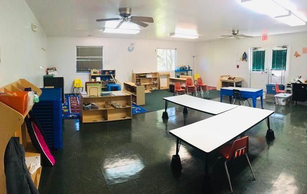 A classroom with tables and chairs and a ceiling fan