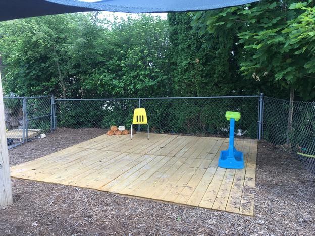 A wooden deck with a yellow chair and a blue stool
