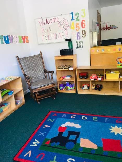 A room with a rocking chair and a rug with a train on it