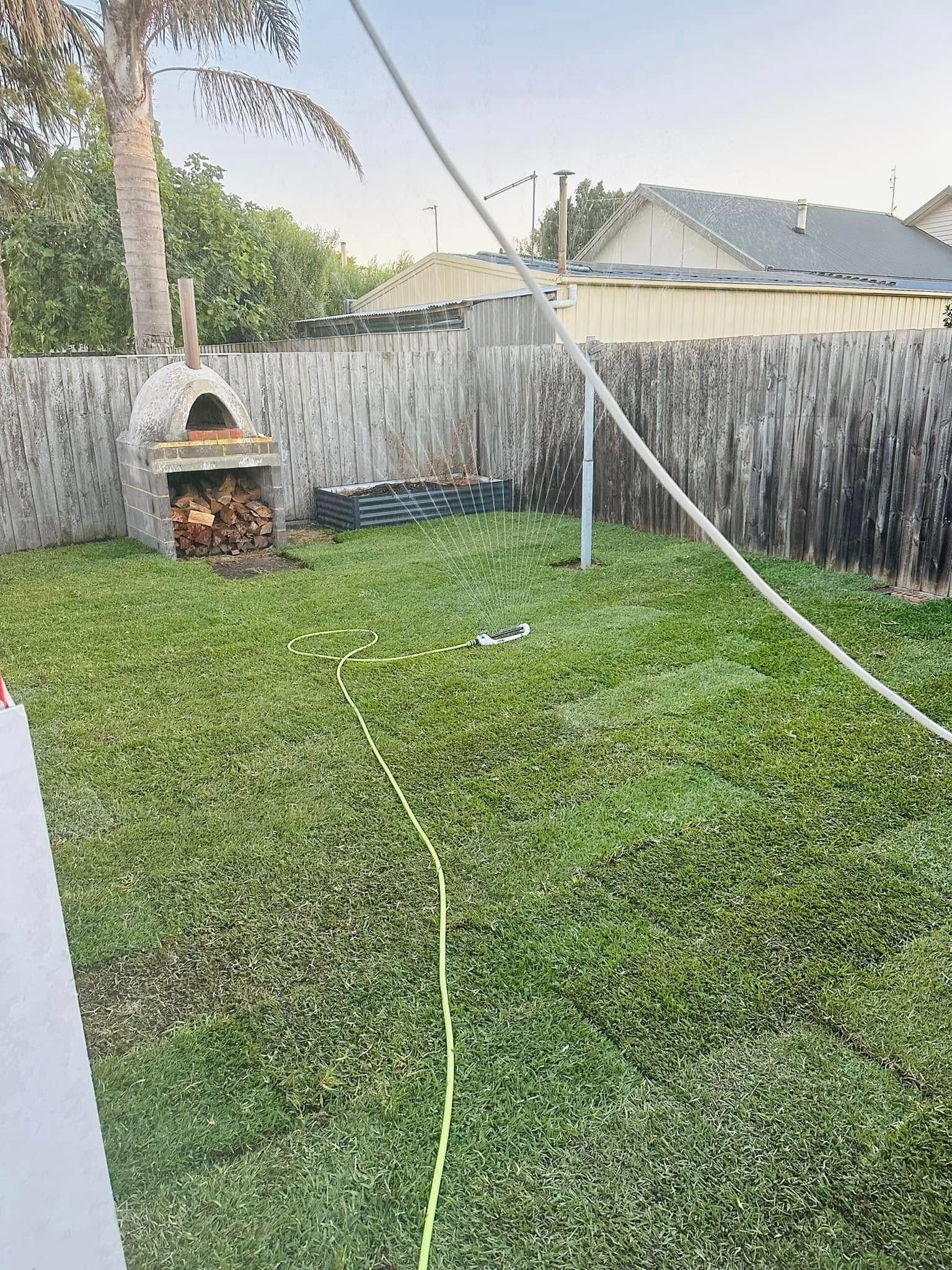 A backyard with a fence and a pizza oven.