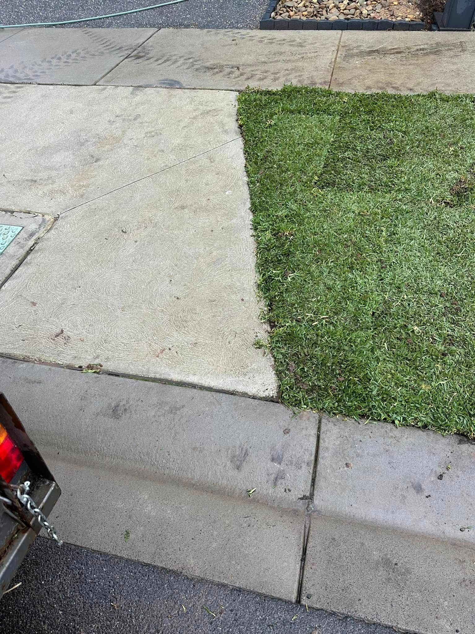 A car is parked on the side of the road next to a sidewalk and grass.