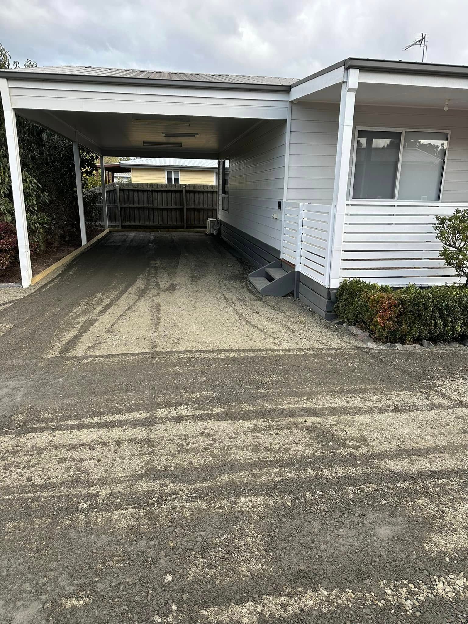 A white house with a carport in front of it.