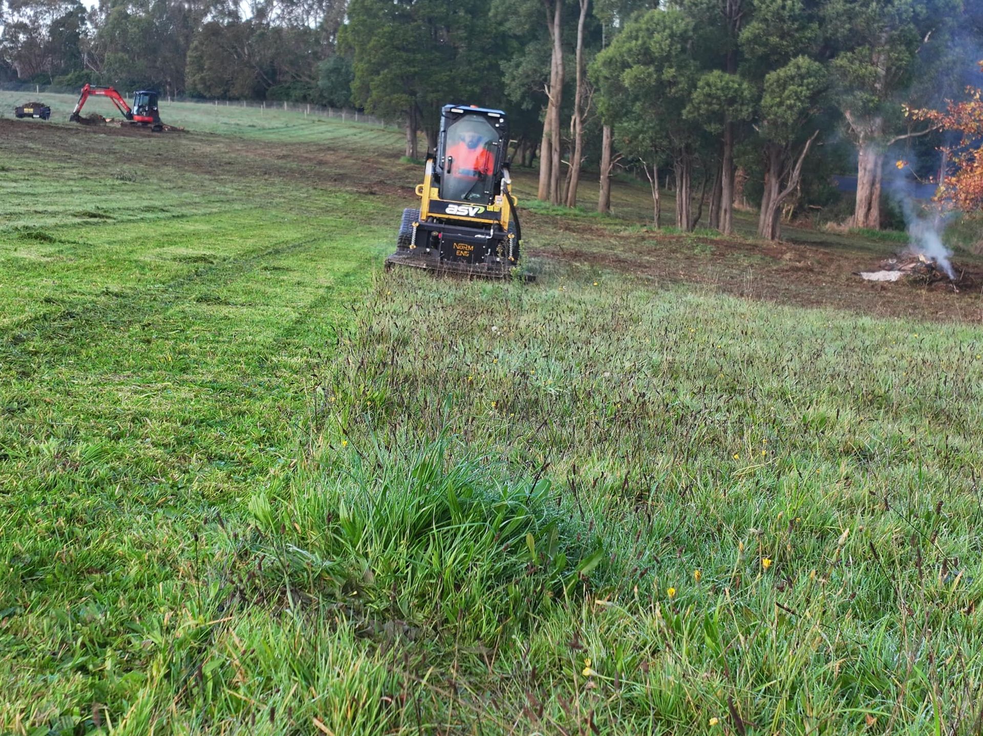 A lawn mower is cutting grass in a field.
