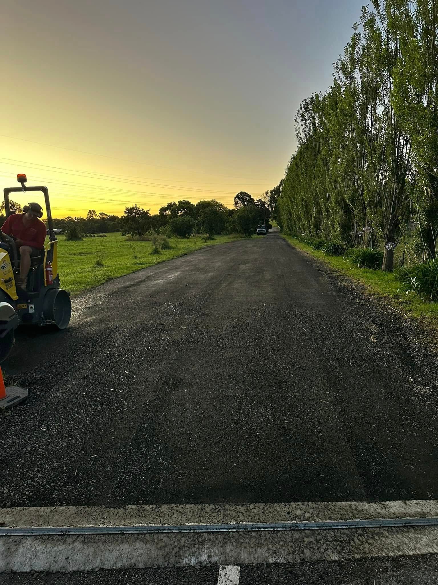 A man is driving a bulldozer down a dirt road.