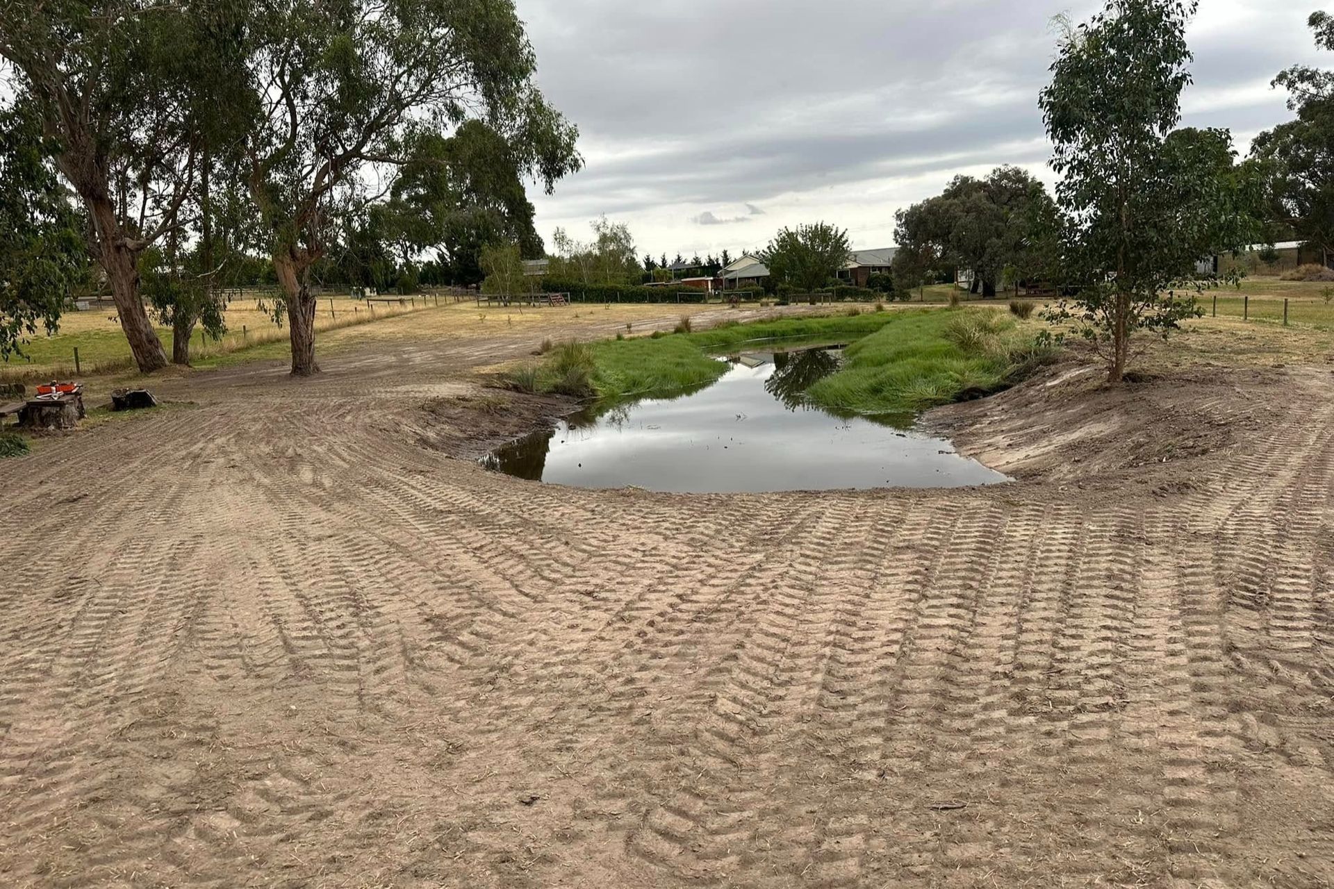 There is a pile of dirt in the middle of a field with trees in the background.
