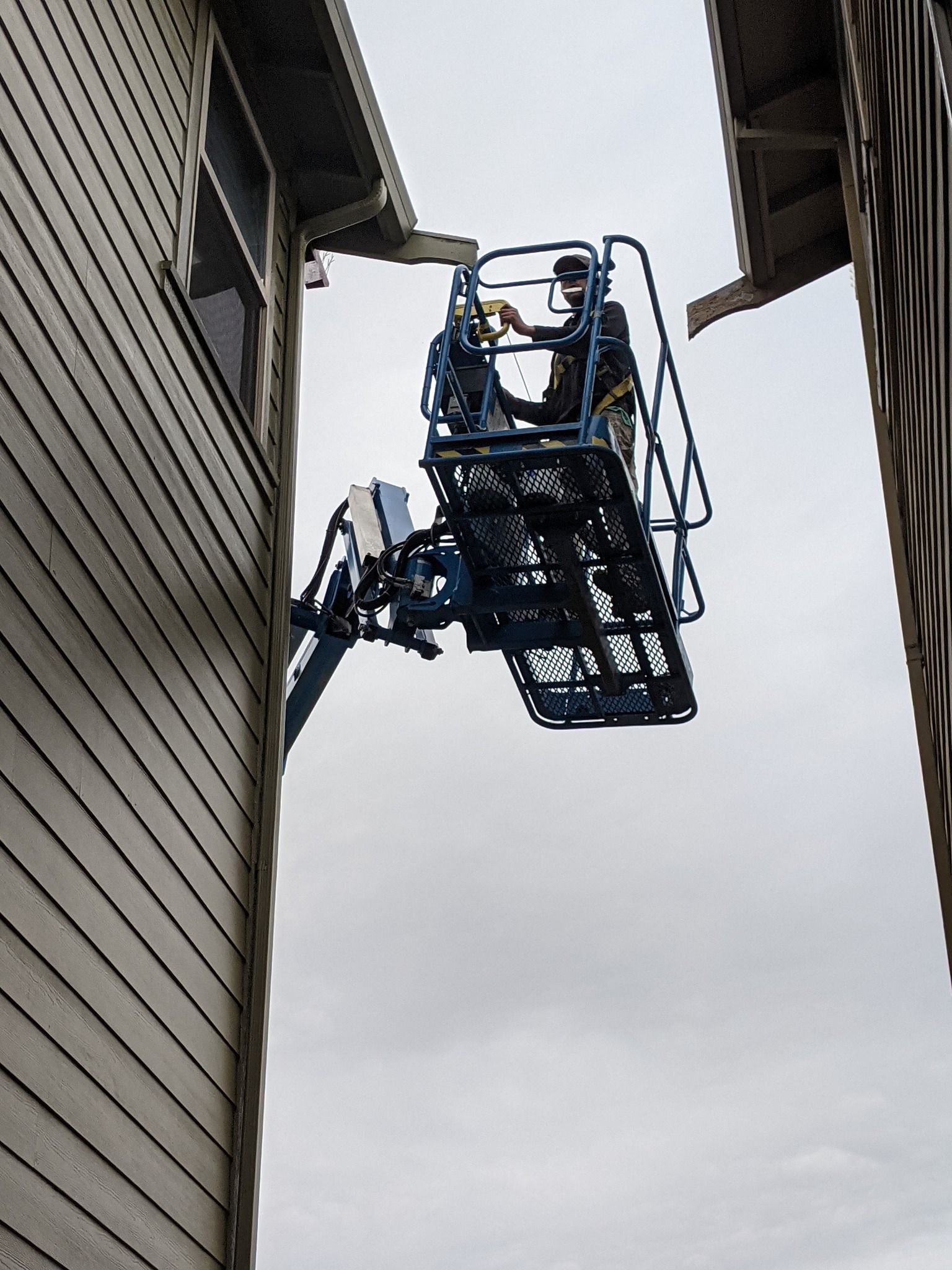 A man is sitting on a lift between two buildings.