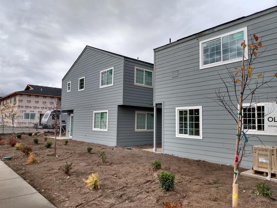 A row of houses with a lot of windows and a tree in front of them.