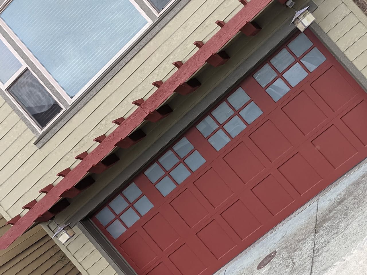 A man is standing on a ladder painting a garage door.