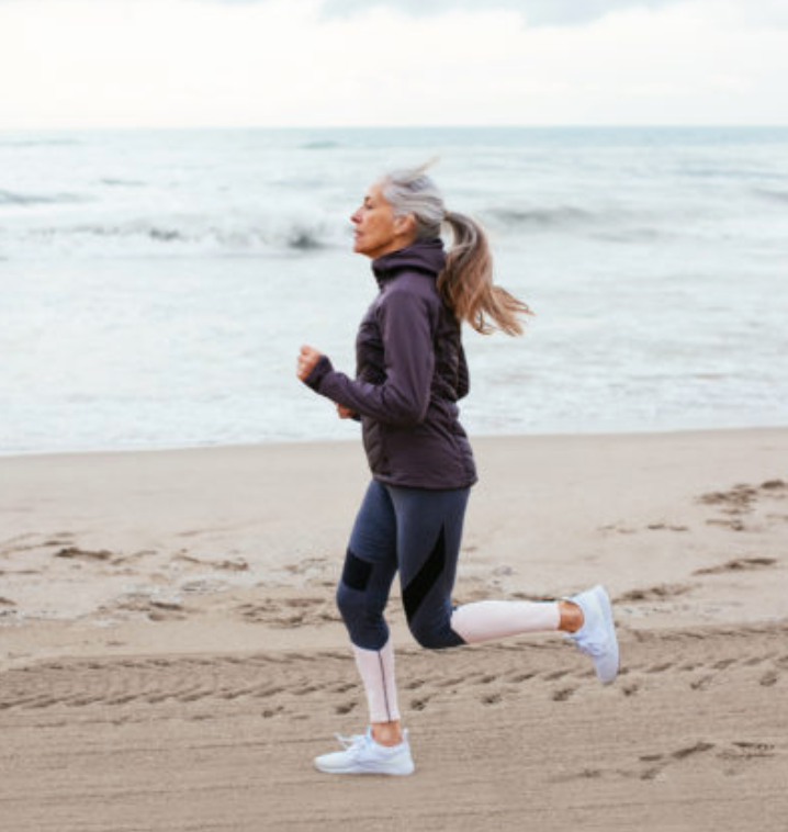 A woman is running on the beach near the ocean