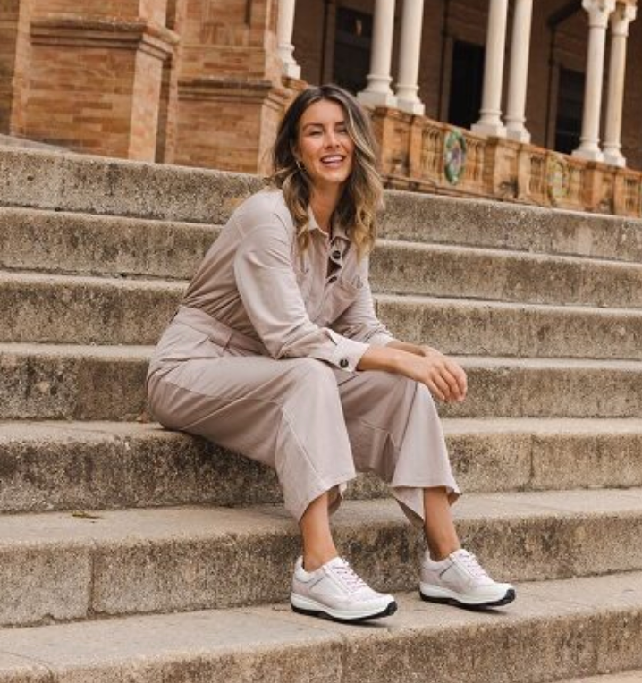 A woman in a jumpsuit is sitting on a set of stairs