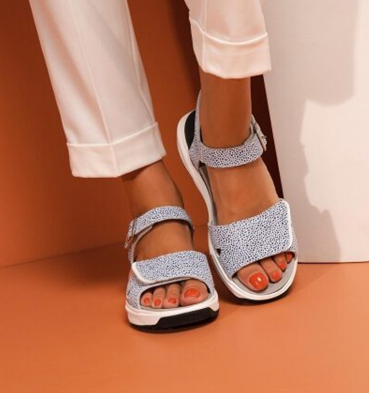 A woman wearing a pair of sandals with orange toenails