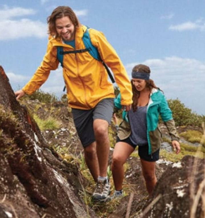A man and a woman are hiking up a rocky hillside