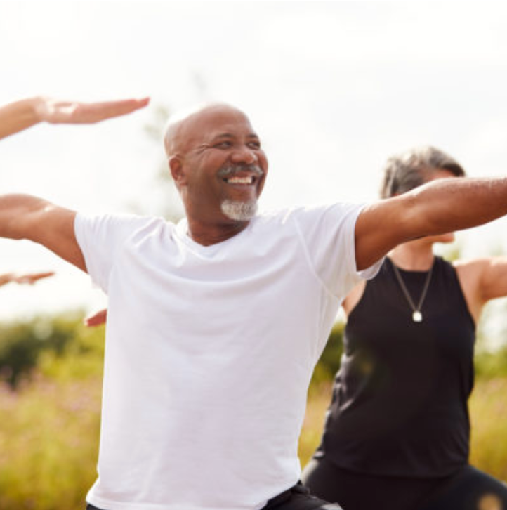 A man and a woman are practicing yoga in a field.