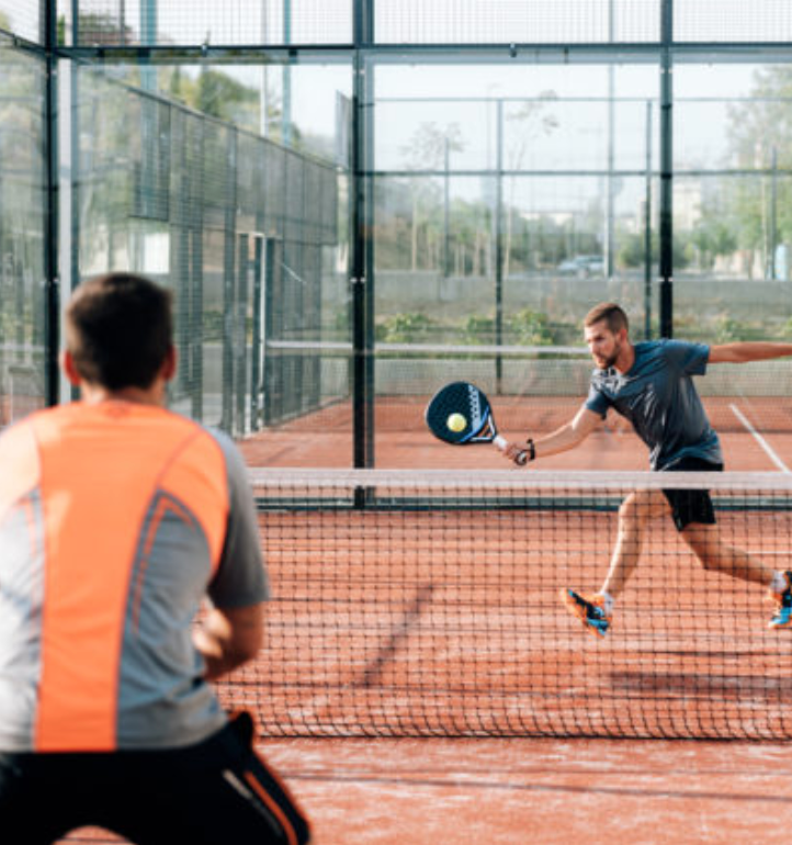Two men are playing paddle tennis on a court.