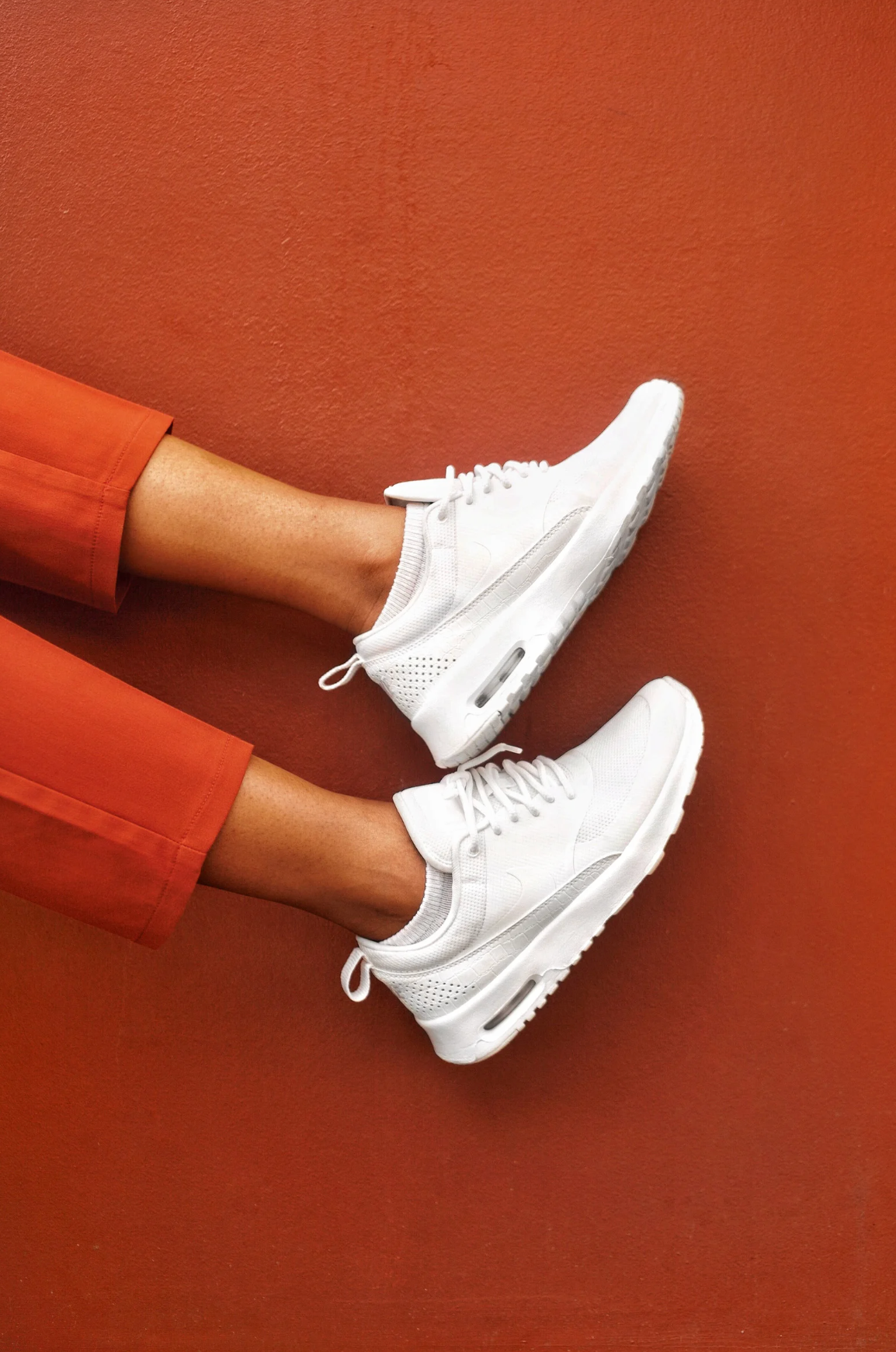 A person is wearing a pair of white nike air max thea sneakers.
