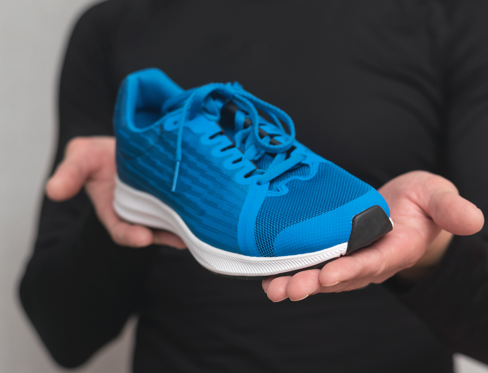 A person is holding a blue running shoe in their hands.