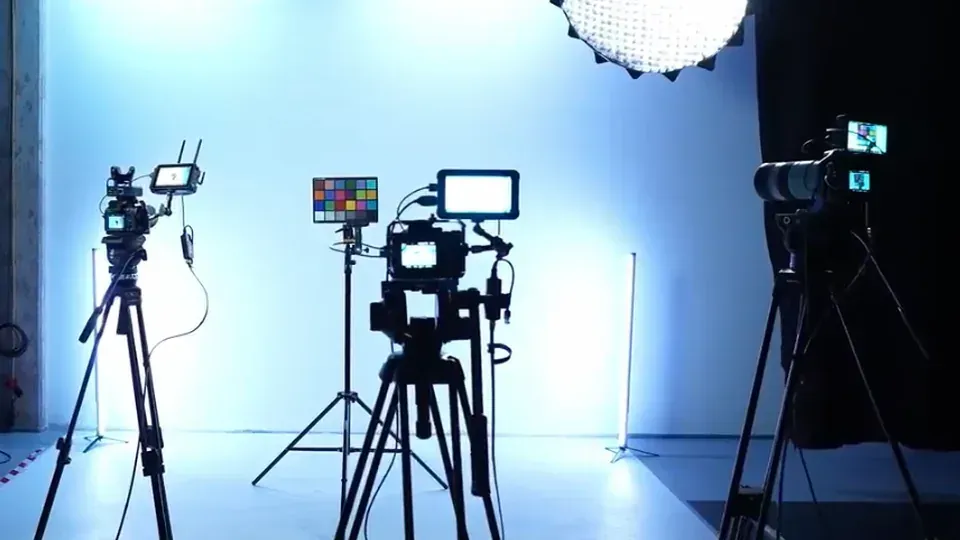 Ein Studio-Setup mit drei Kameras auf Stativen, einer Farbkarte und professioneller Beleuchtungsausrüstung.