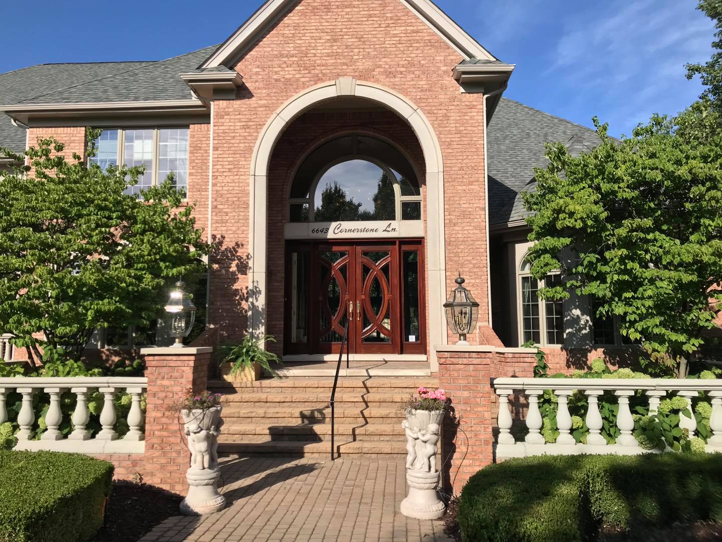 A large brick house with a wood door professionally stained