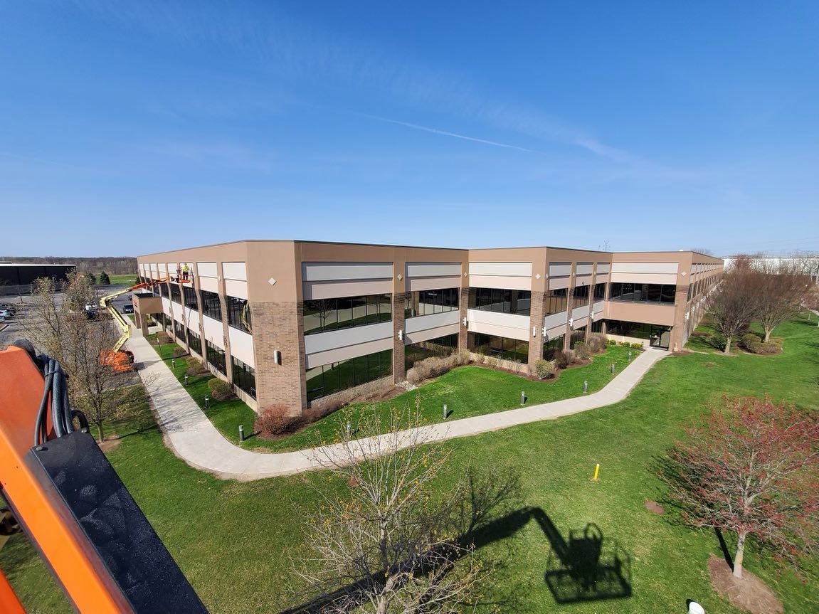 Exterior of a commercial building being painted tan and white by a professional painting company