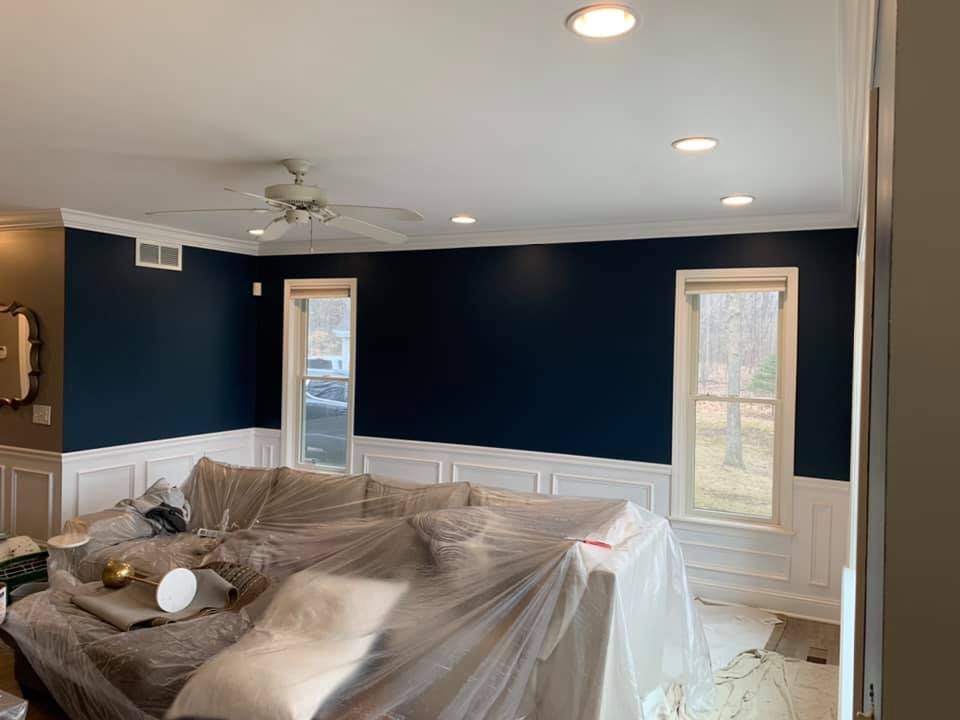 A house painters finished work of a living room with wainscoted walls painted navy and white