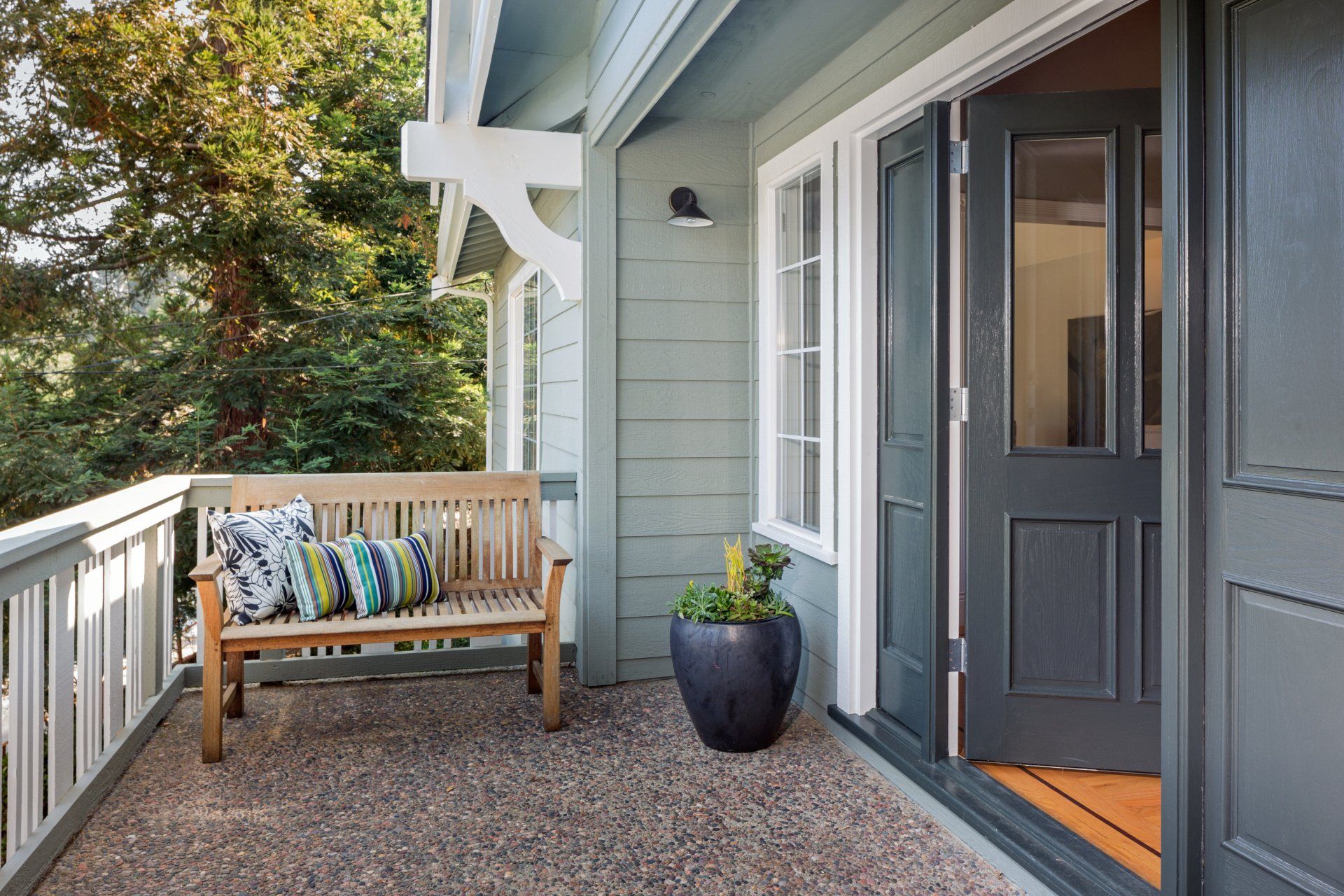 A residential home with a freshly painted grey door, blue siding and white window trim painted by an expert painter